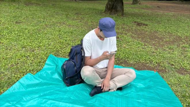 Shoji Morimoto assis dans l'herbe