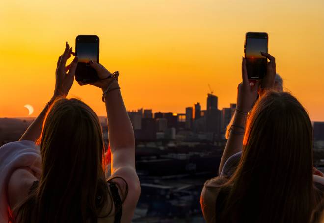 Jeunesfilles photgraphiant une &eacute;clipse solaire partielle au-dessus de la tour Eiffel