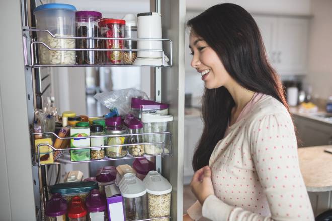 Jeune femme regardant dans son placard de cuisine