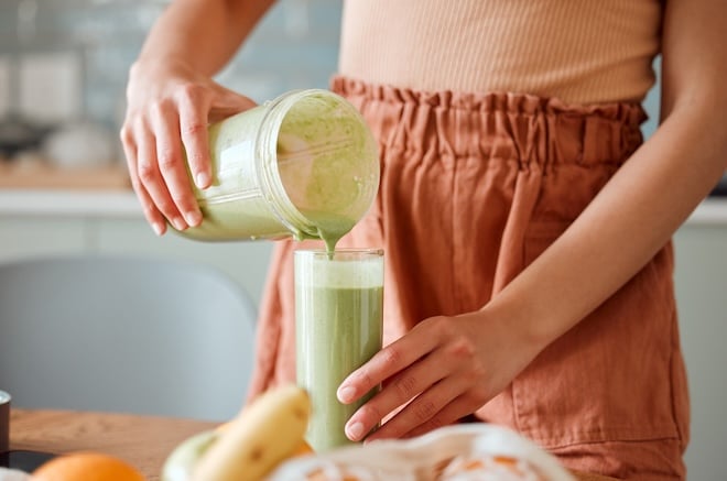 une femme versant un smoothie d&eacute;tox dans un verre