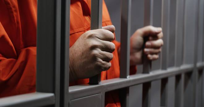 Mains d'un prisonnier tenant les barreaux de la prison