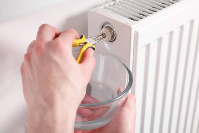 Personne r&eacute;parant un radiateur avec une pince