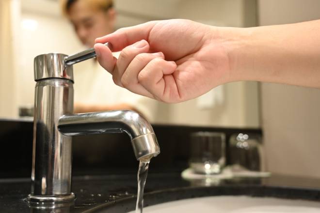 Homme ouvrant un robinet avec un jet d'eau coulant