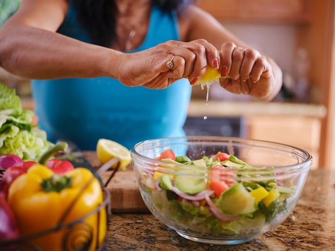Femme ajoutant du jus de citron dans une salade