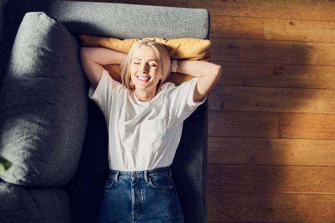 Jeune femme allong&eacute;e sur le canap&eacute; se relaxant et souriant