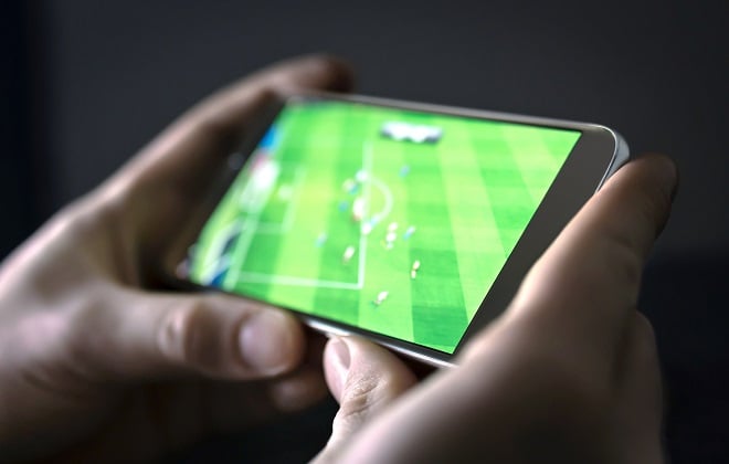 Homme regardant du foot sur son téléphone