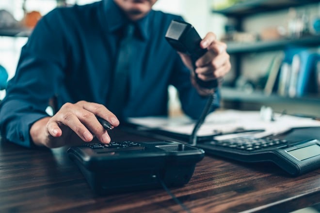 Homme composant un numéro sur un téléphone fixe