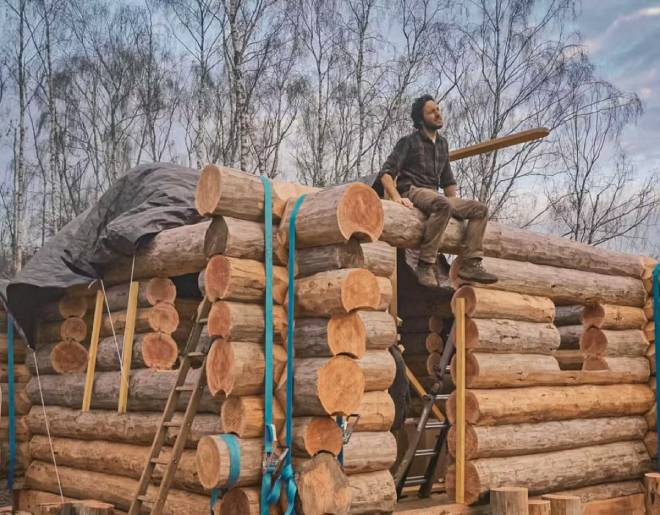 Vianney assis sur sa cabane en bois en construction