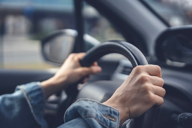 Mains tendues d'une conductrice sur levolant d'une voiture