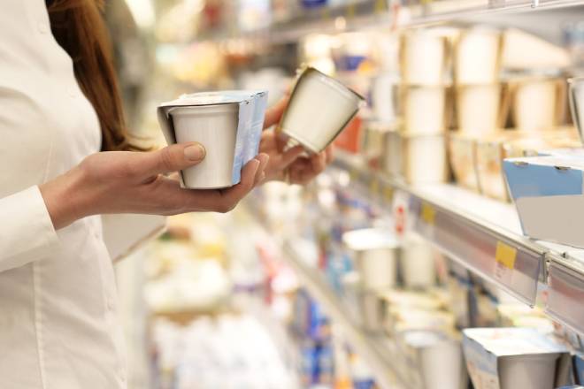Jeune femme comparant les yaourts en magasin